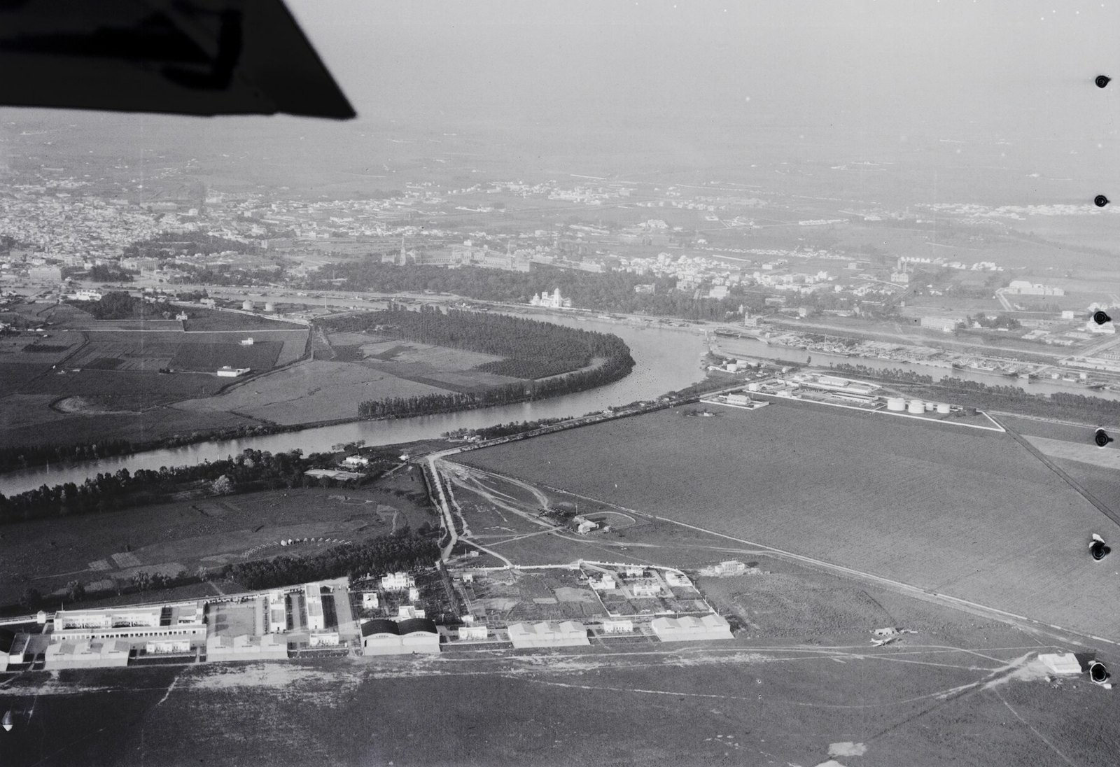 Imagen 10. Sevilla y el aeródromo de Tablada vistos desde el sur, a 400 metros de altura, en mayo de 1928. En primer plano, los hangares y edificios de Tablada; detrás, el Guadalquivir y la ciudad.